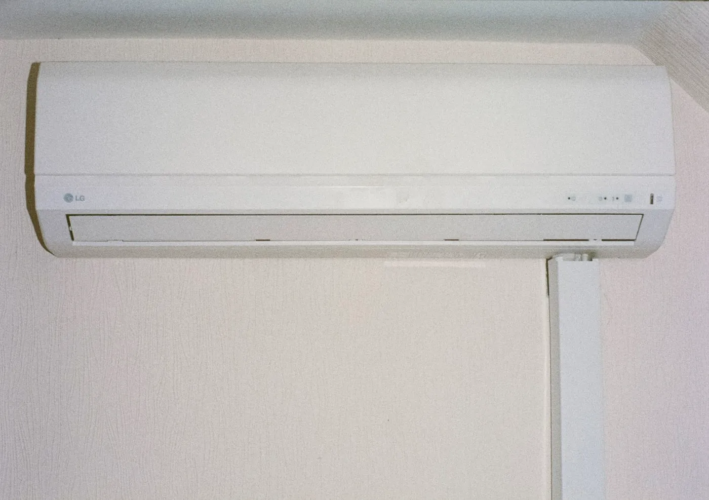 Ductless mini-split indoor unit mounted high on a plaster wall