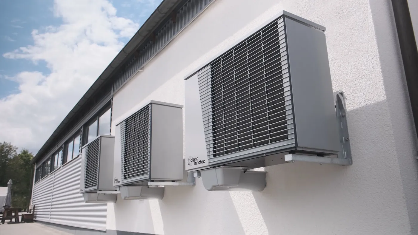 New cold-climate heat pump installed on a composite pad beside a brick home