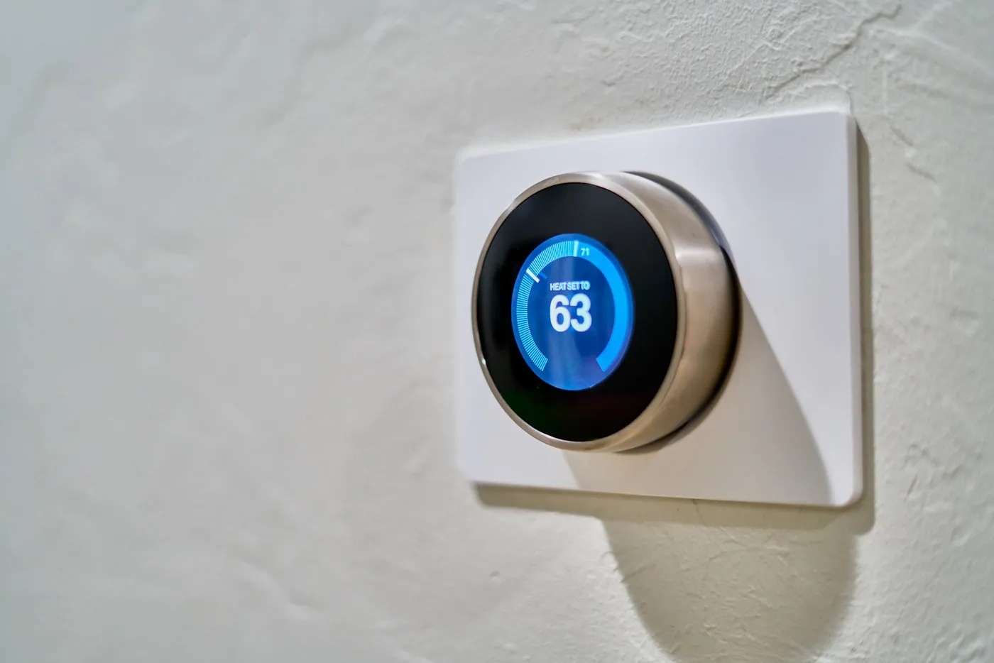 Smart thermostat mounted on a hallway wall showing cooling mode